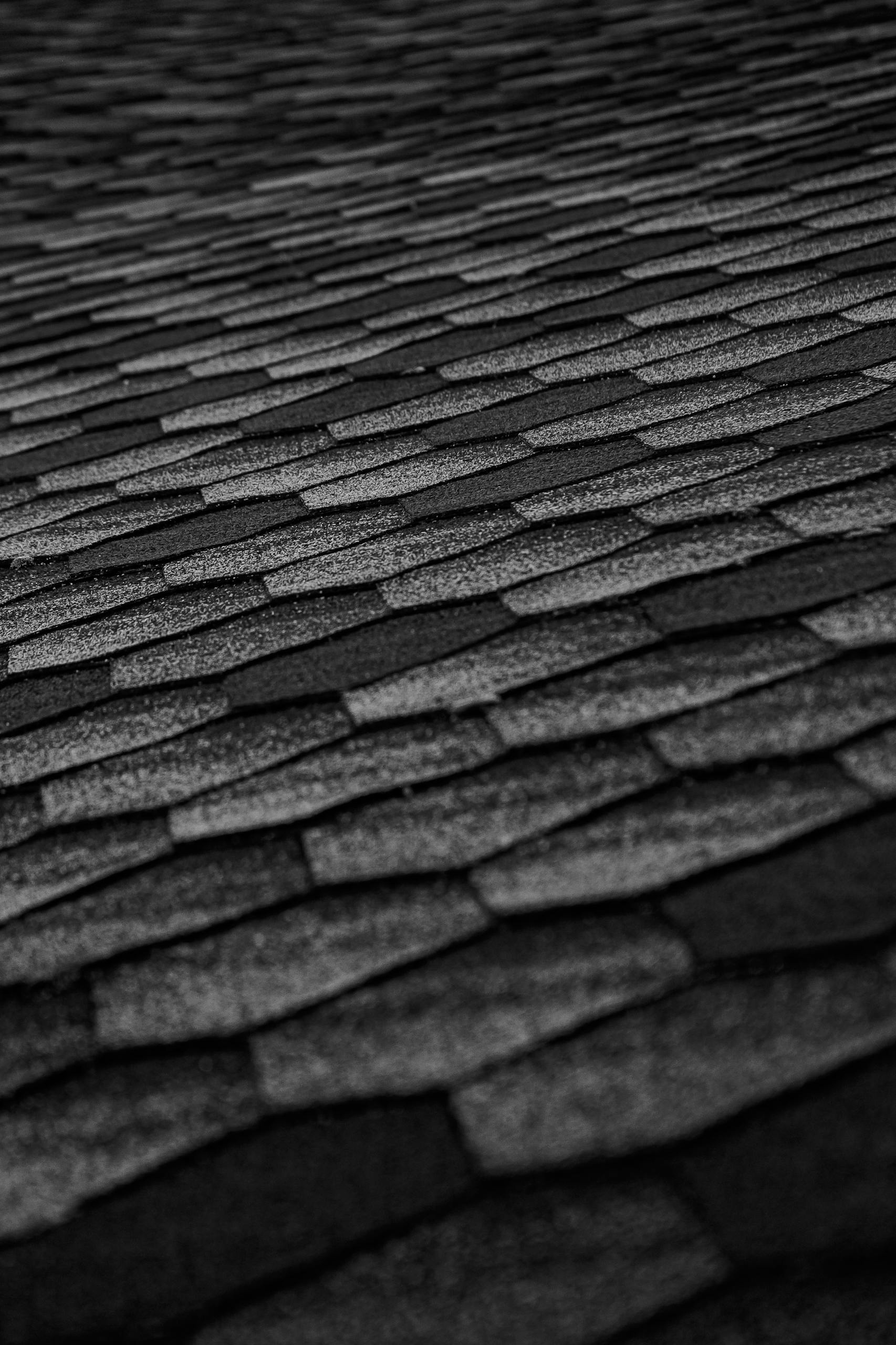 Close-up of black roof shingles forming an abstract textured pattern, emphasizing geometry and modern architecture.